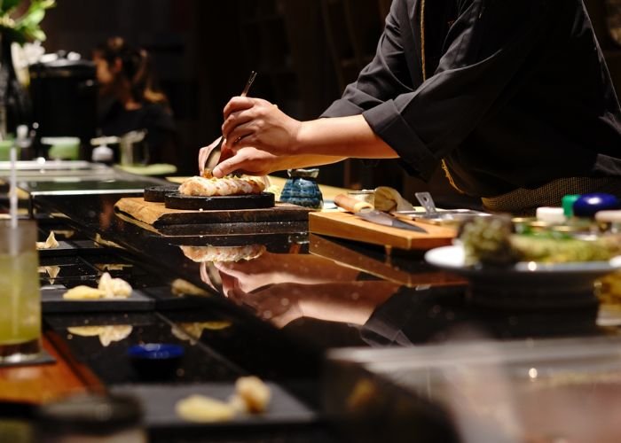 A chef preparing uni nigiri in a sushi restaurant in Japan