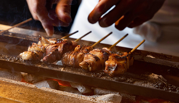 Grilled skewers cooking over open coals in a restaurant