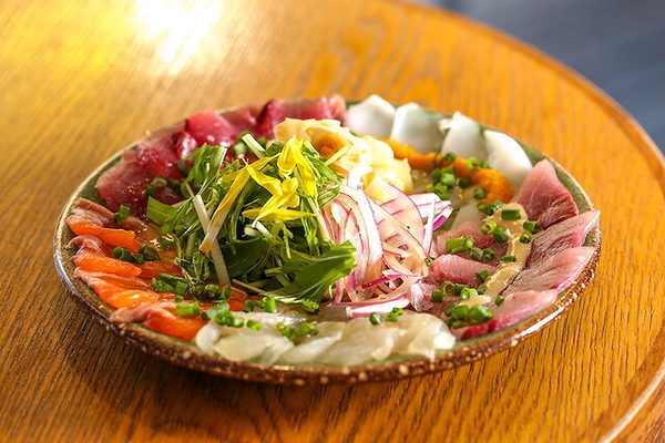 Colorful sashimi plate with fresh greens on wooden restaurant table