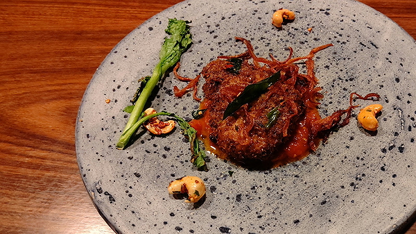 Gourmet beef dish with greens and nuts on stoneware plate