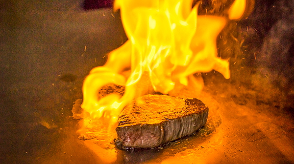 Flame-seared steak on grill at a gourmet restaurant
