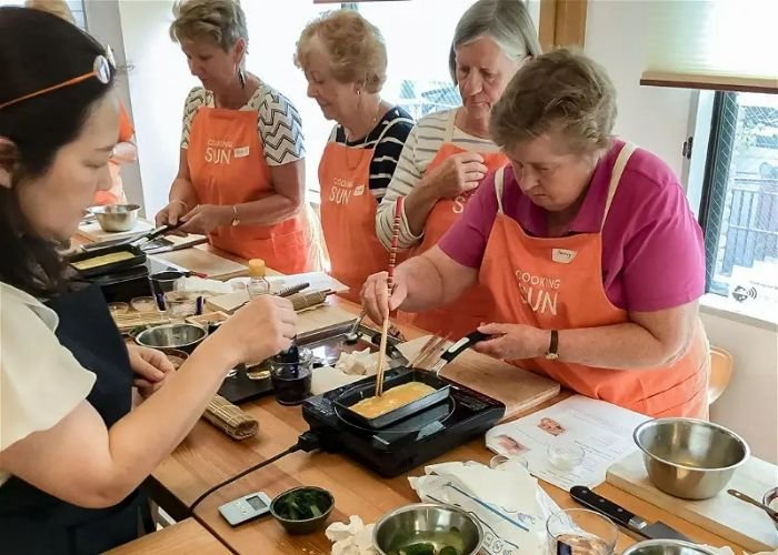 A group of ladies are learning how to make sushi in a sushi-making class.