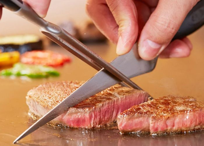 A chef preparing a steak at Katsura Steak House.