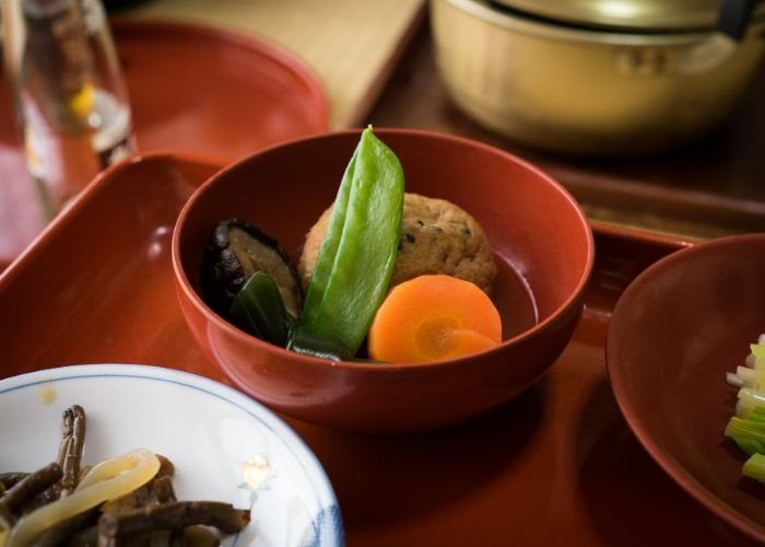 A close-up shot of a shojin ryori set meal, showing food in a traditional red lacquer bowl.