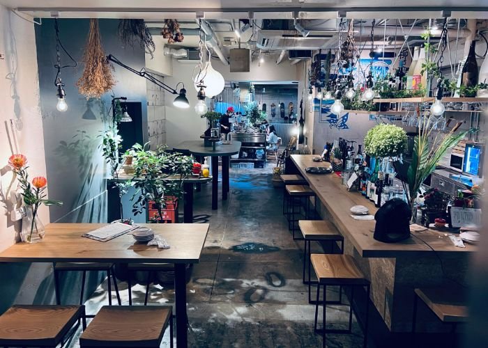 The interior of Michi Naki Michi in Shibuya, featuring industrial style, warm woods, and many plants.