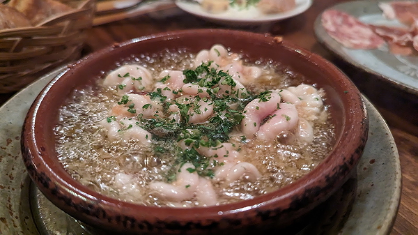 Sizzling shrimp dish in clay pot with herbs and olive oil