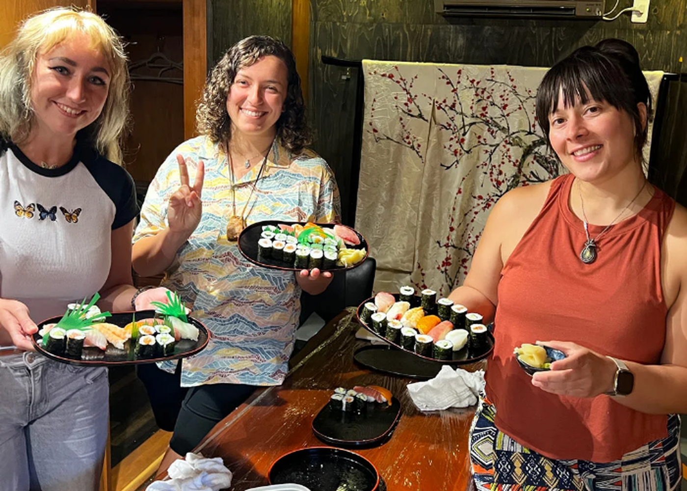 Three people smiling at a private sushi cooking class in Kyoto. One is doing a peace sign.