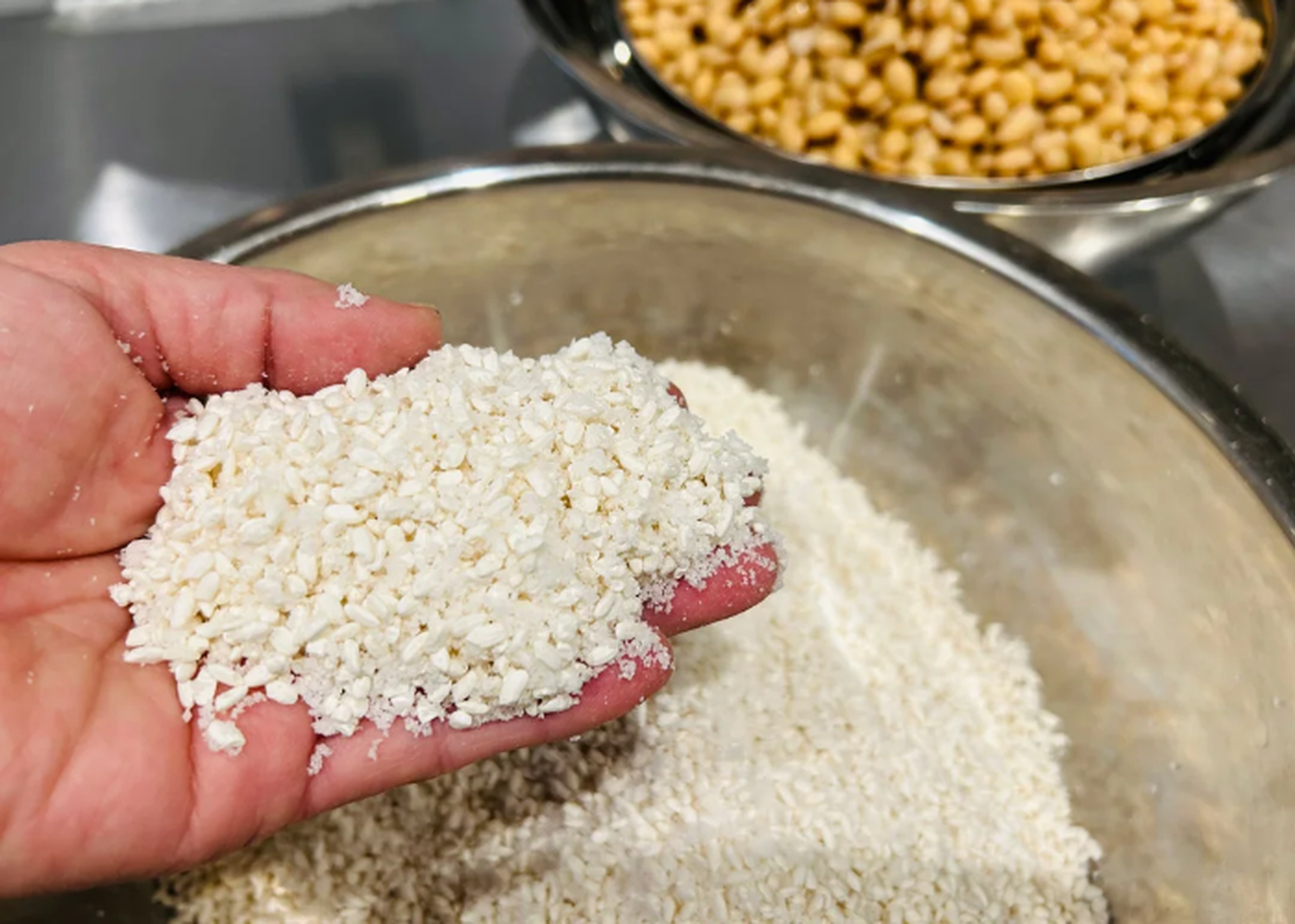 A hand reaches into a bowl of rice, preparing to make kome miso.