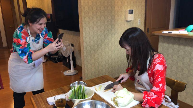 Someone taking a picture of their friend as they cook in a Japanese cooking class.