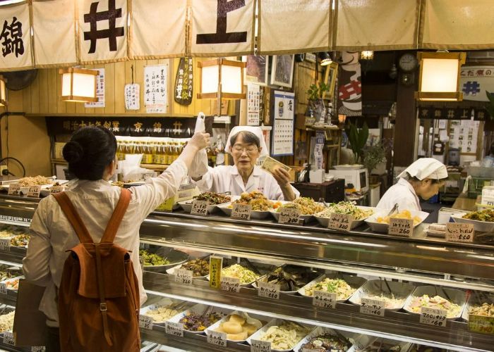 A customer is being handed a bag from one of the small stores in Kyoto's Nishiki Market.