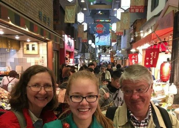 A family smile at the camera, enjoying their Nishiki Market food tour.