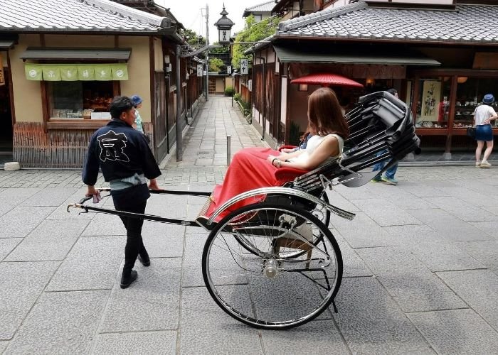 A man pulls a women through the streets on Kyoto in a private rickshaw food tour.