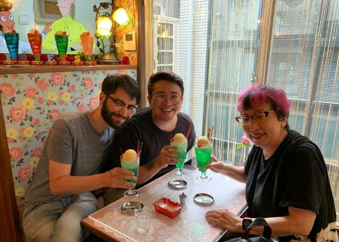 A tour guide and two guests smile while sitting in one of Kyoto's cozy cafes.