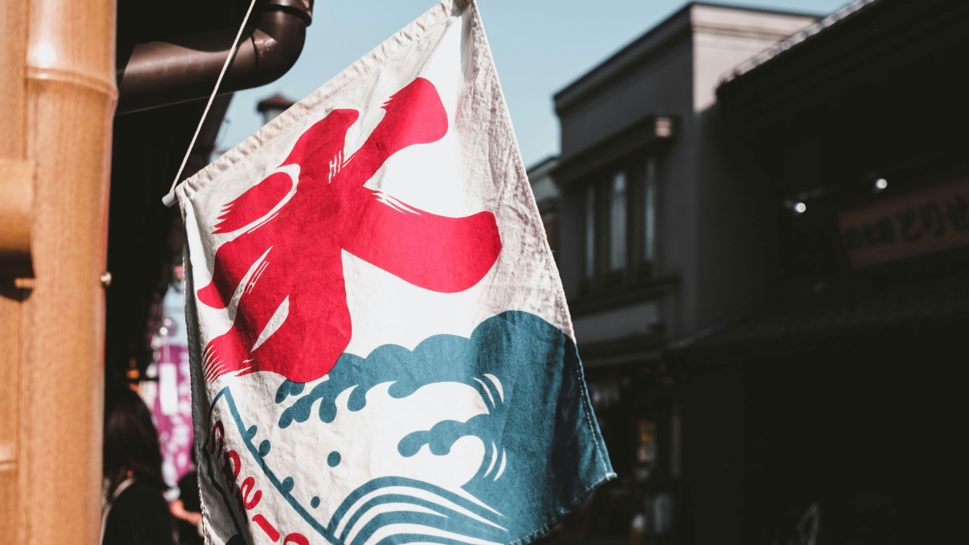 Japanese street scene with a colorful flag featuring kanji and waves