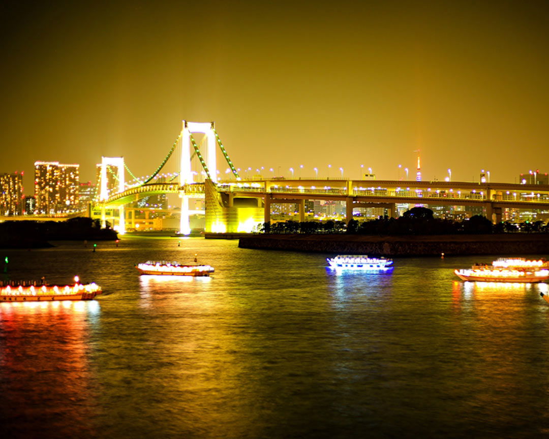 Tokyo Bay, alight at night, while people traverse in traditional yakatabune boats.