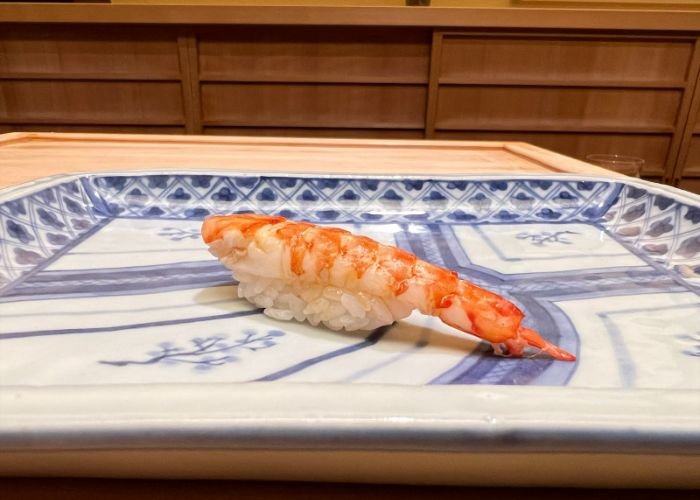 A vivid, fresh nigiri sushi, served on a blue and white plate.
