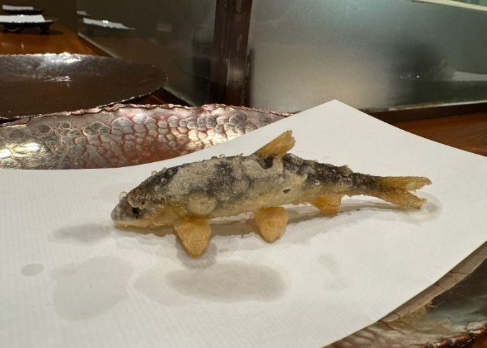 An entire fish has been deep-fried, appearing to stand up on the plate using its fins.