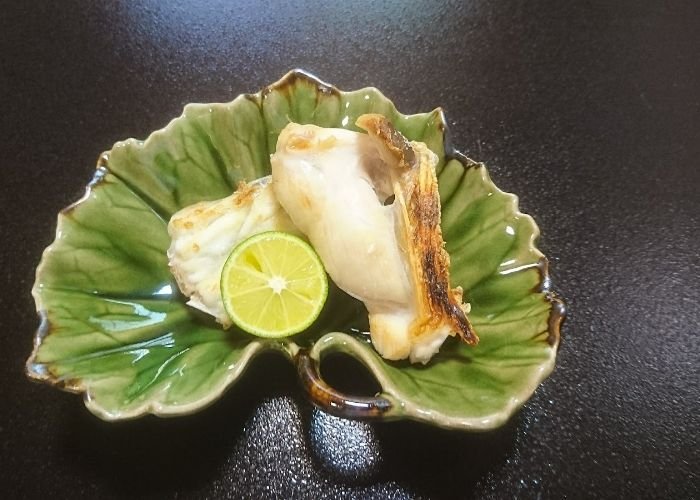 A serving of Michelin star puffer push, served with a wedge of lime in a leaf-shaped serving tray.
