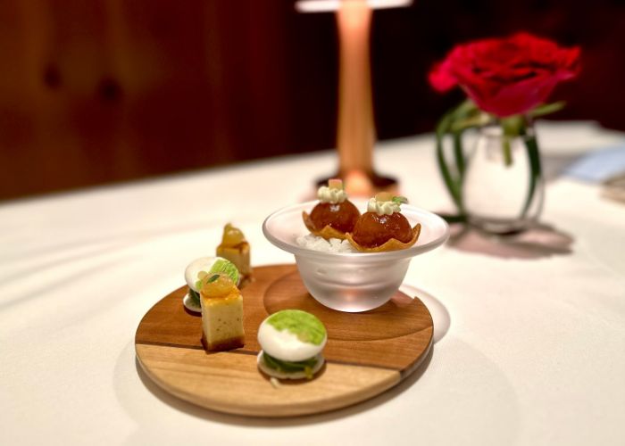 A selection of French desserts on a wooden serving board. Behind them, a blooming rose and the warm glow of a lamp.