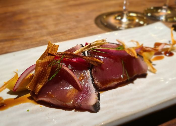 Rare meat with a beautiful garnish, served on a white tray.