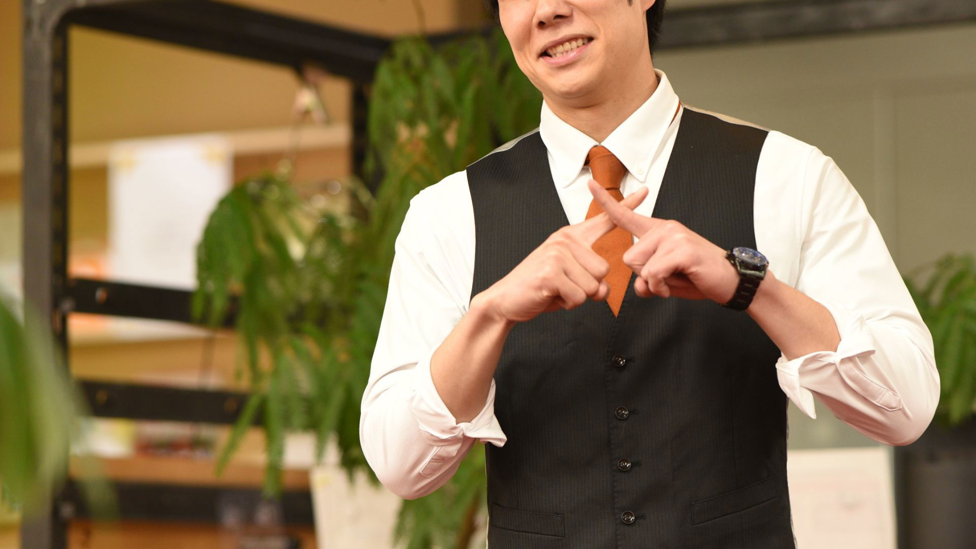 Man in a suit gestures with fingers in an office setting
