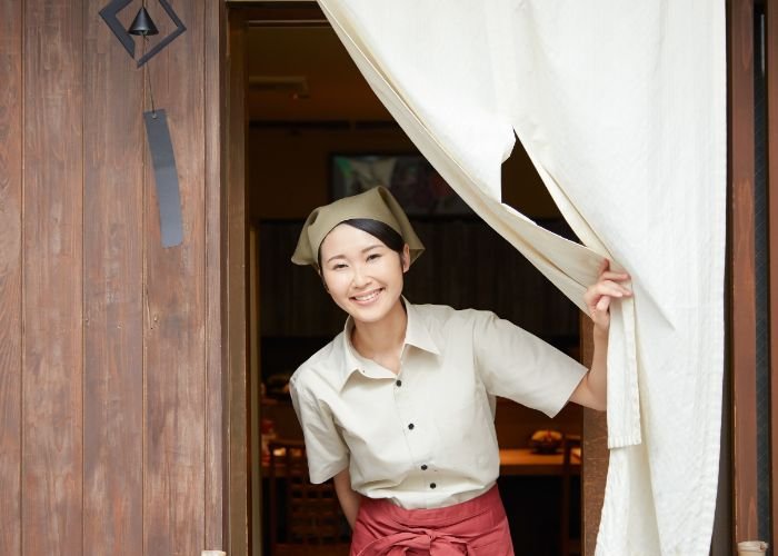 A restaurant worker welcomes customers at a restaurant in Japan.