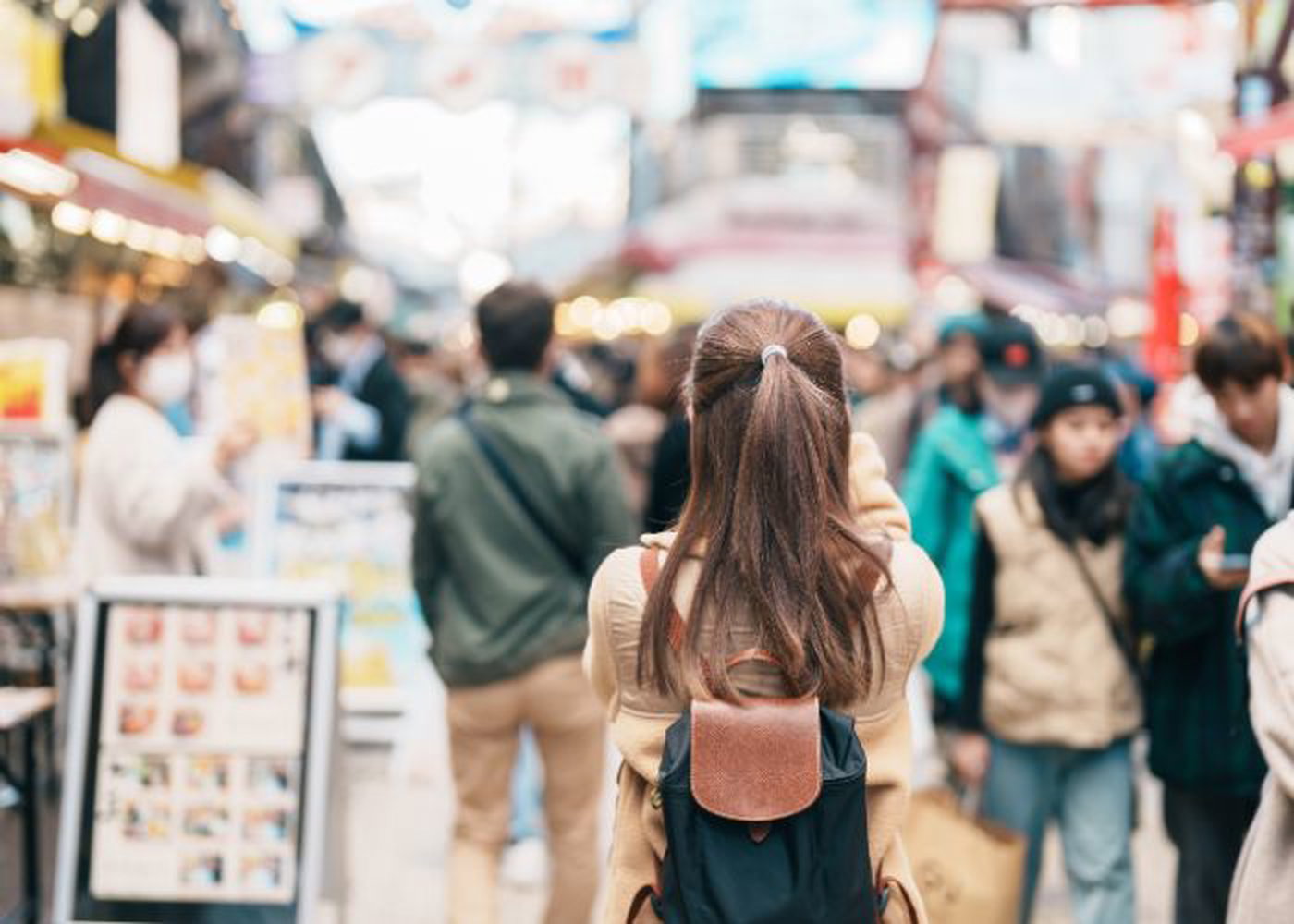 A woman walks down a crowded street in Japan.