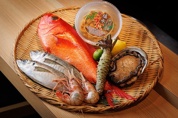 Fresh seafood platter with fish, shrimp, and abalone on wooden table