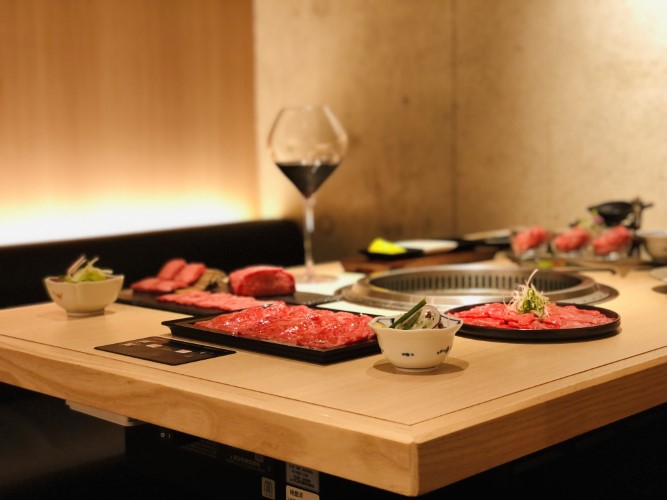 A table covered in yakiniku meats, drinks and a grill at its center at Yakiniku Mutsumi.