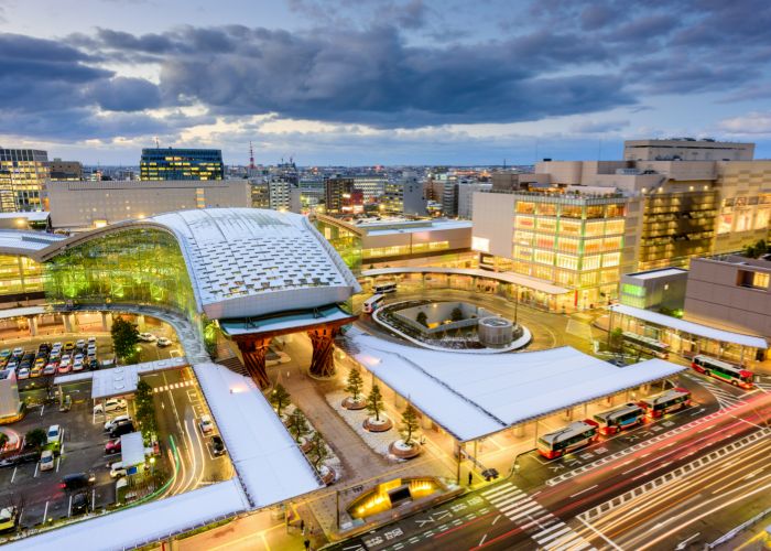 A high-up shot of central Kanazawa, showing the city lit up as the sun begins to set.