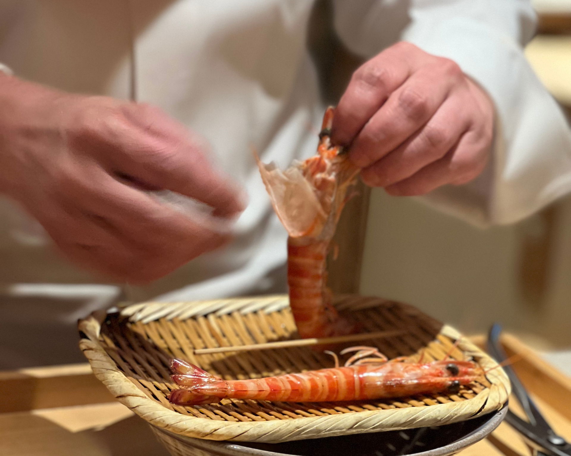 An expert chef preparing shrimp at Gion Sushi Tadayasu.