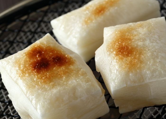 A close-up of yakimochi, with cubes of grilled mochi on a grill.