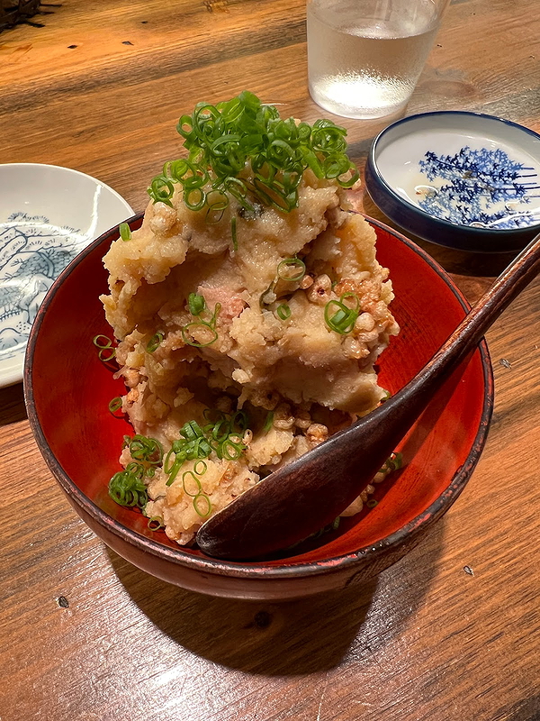 Crispy tempura with green onions served in a red bowl on wooden table