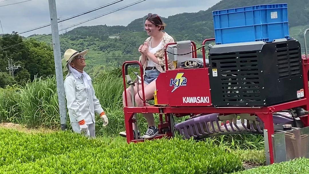 A girl sitting on farming equipment at a tea plantation in Japan