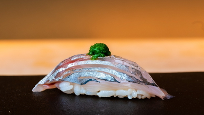 Delicate sushi piece with silver fish and green garnish on rice
