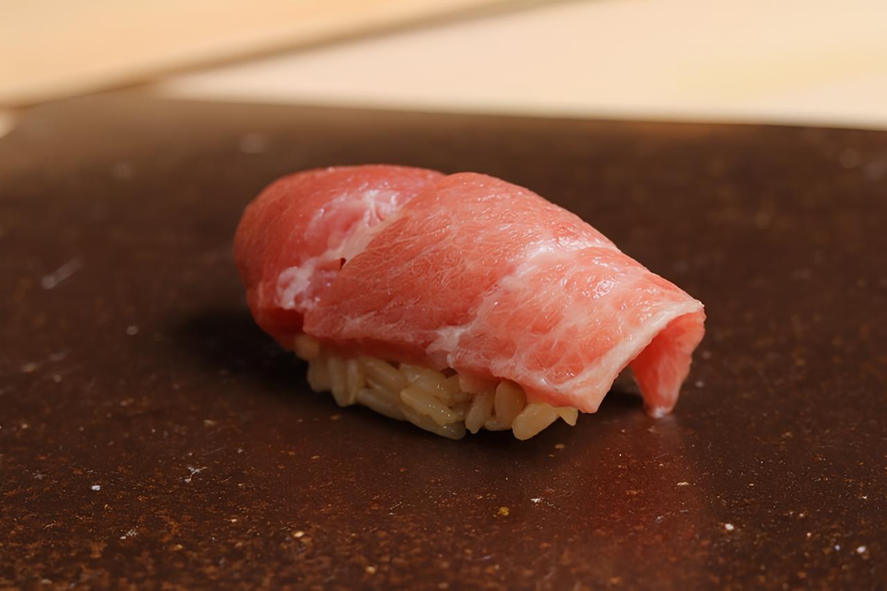 Fresh tuna sushi on brown board, highlighting premium seafood dish.