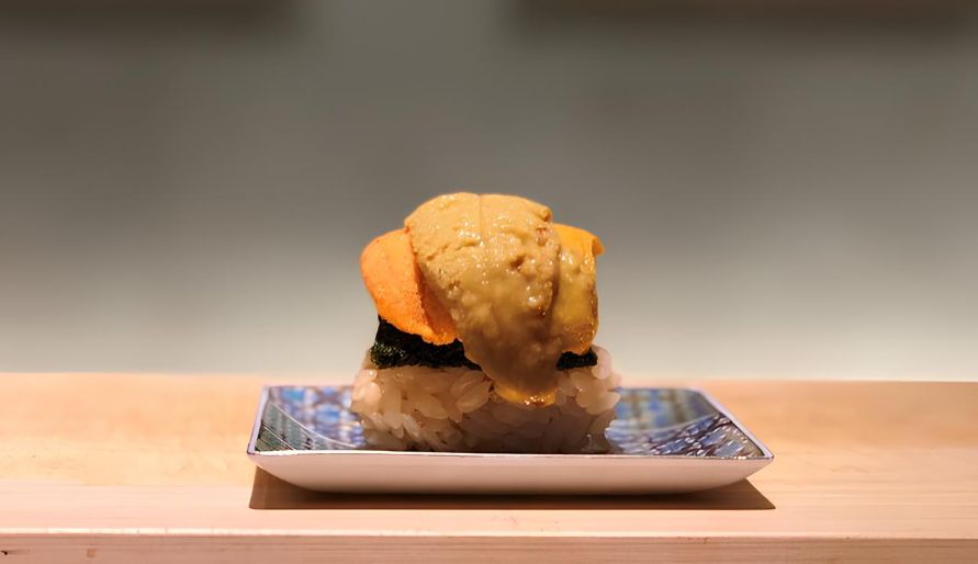 Uni sushi plated elegantly on a patterned dish