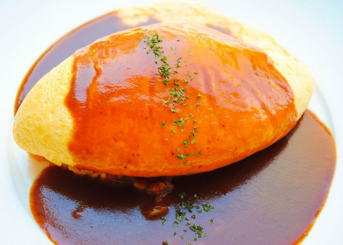 A Japanese omuraisu dish, with an omelet that's covered in a shiny, demiglace sauce.