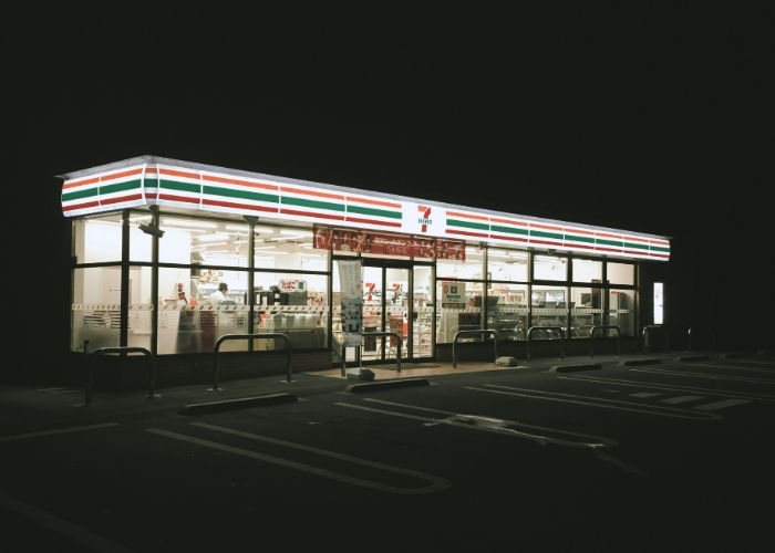 A Seven-Eleven konbini in Japan at night. Its lights shine out into the darkness.