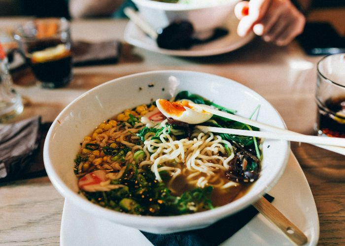 A bowl of ramen with noodles, seaweed, fishcakes, onions, and soft-boiled eggs on top.