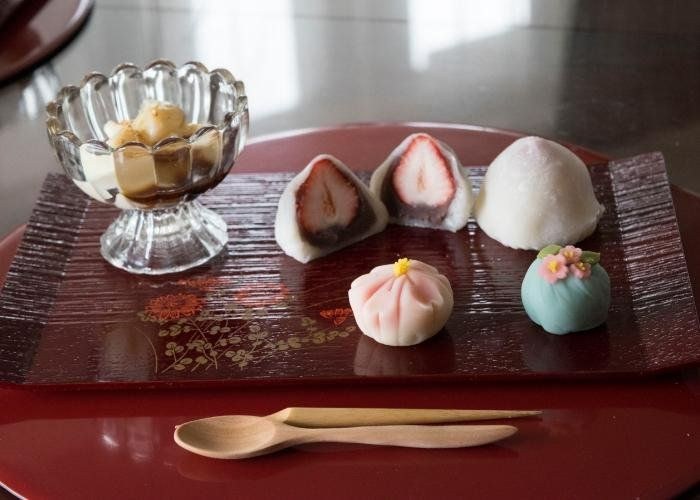 A selection of Japanese desserts are laid out on a serving tray, including wagashi and mochi.