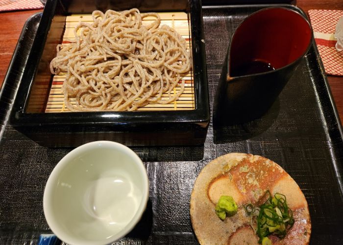 A soba serving tray at Tamawarai, including soba, spring onion, wasabi, and more.