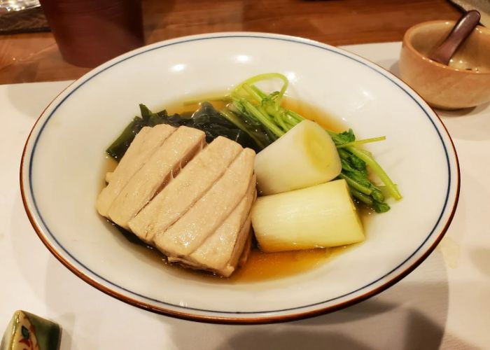 Hot pot at the Michelin star nabe restaurant in Tokyo, Negima. It features tuna, leek, and greens in a broth.
