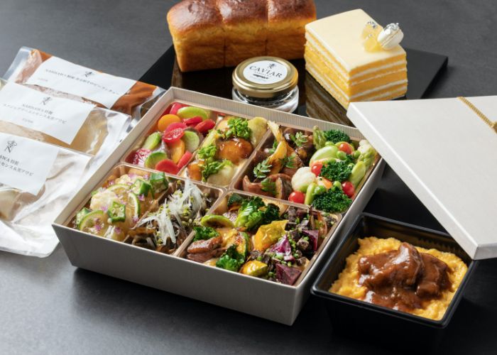 A bento box-style serving at Narisawa, filled with colorful, fresh vegetables, bread, and cake.