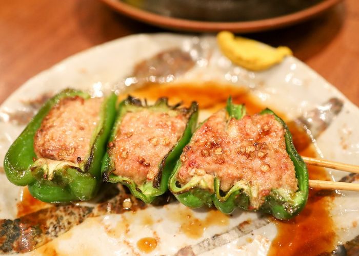 A skewer at Torishige, featuring grilled meat inside a green pepper.