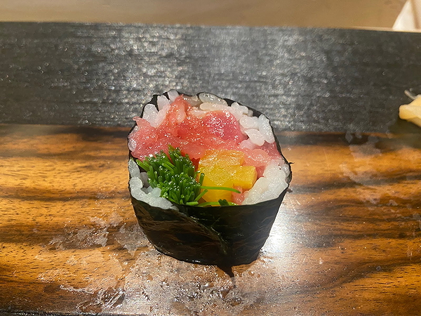 Fresh sushi roll with tuna, rice, and seaweed on wooden table