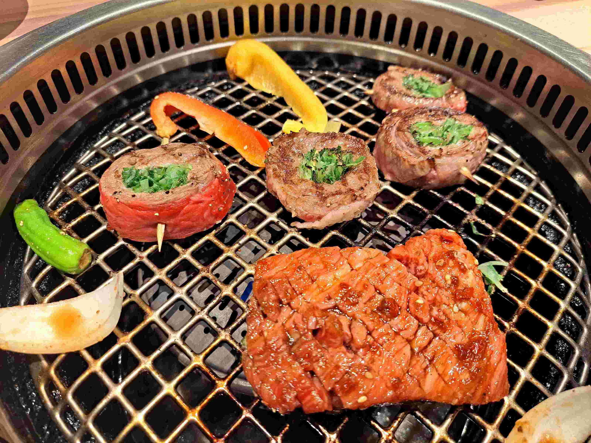 Premium wagyu beef and vegetables being skewered and grilled in this yakiniku experience.