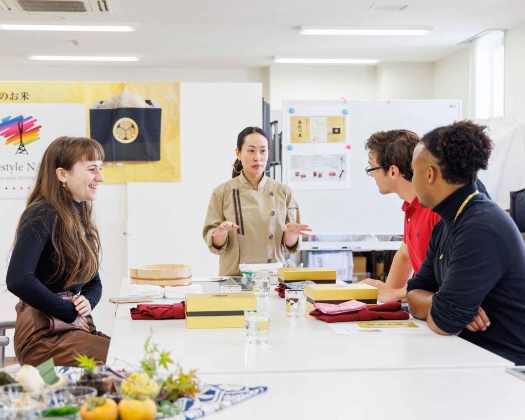 Smiling guests listening to their expert host explain how to make vegan onigiri.