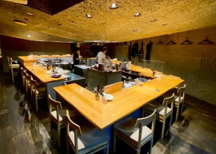 The communal dining area of Falo, with rectangular seating area surrounding a central kitchen.