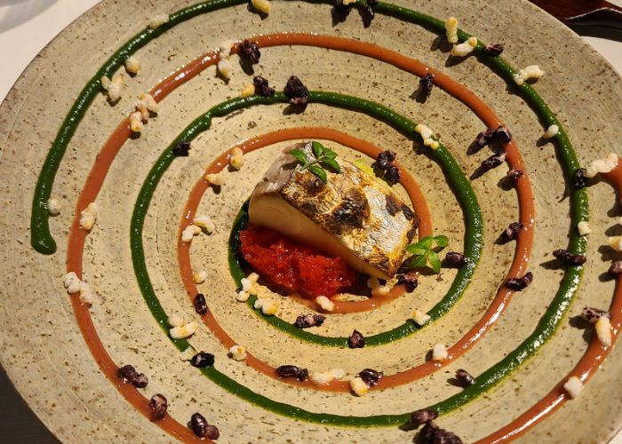 A dish at Narisawa, featuring some kind of vegetable at the center of a plate, surrounded by spirals of sauce.